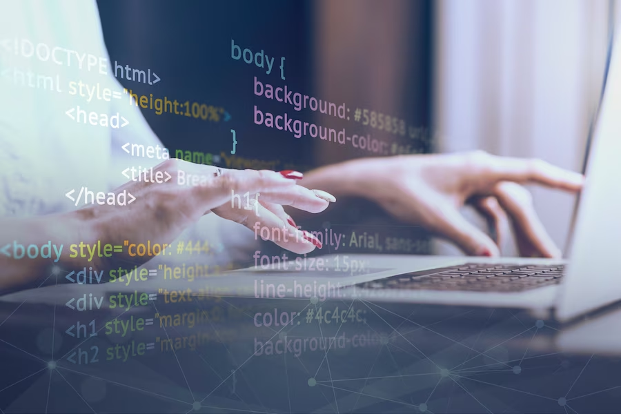 Hand typing on a laptop with code graphic overlay